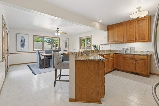 5409 Aldrich Ave S, Minneapolis, MN 55419 - kitchen featuring a peninsula, light stone countertops, healthy amount of natural light, a kitchen breakfast bar, and recessed lighting