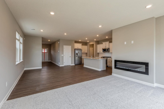10049 73rd Ln NE, Otsego, MN 55330 - unfurnished living room featuring baseboards, recessed lighting, a sink, dark wood finished floors, and dark carpet