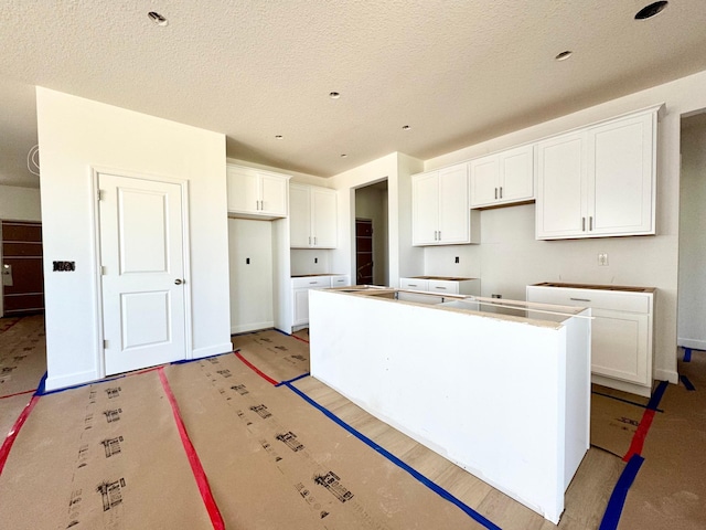 10049 73rd Ln NE, Otsego, MN 55330 - kitchen with a kitchen island, white cabinetry, and a textured ceiling