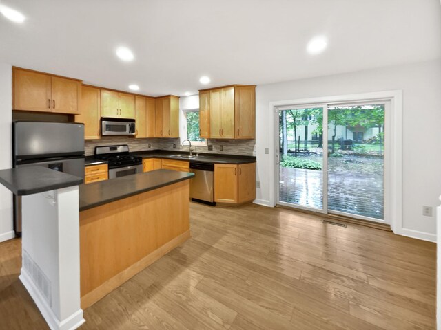 7040 Winfield Rd, Rockford, MN 55373 - kitchen with stainless steel appliances, dark countertops, decorative backsplash, a sink, and light wood finished floors