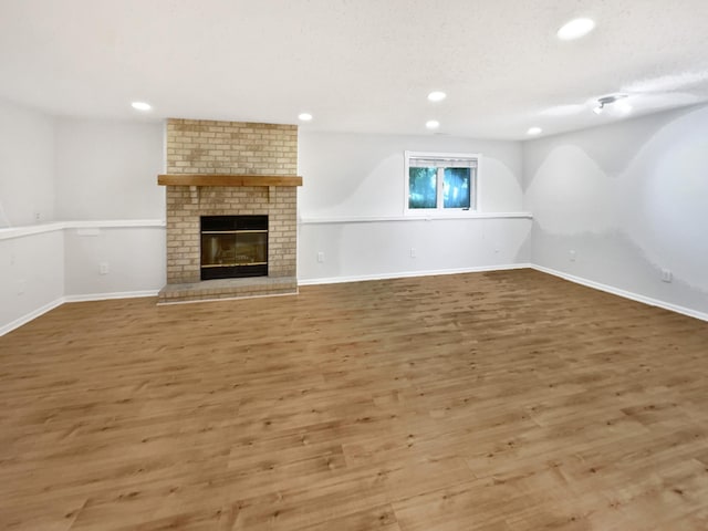 7040 Winfield Rd, Rockford, MN 55373 - unfurnished living room featuring recessed lighting, wood finished floors, a brick fireplace, baseboards, and a textured ceiling