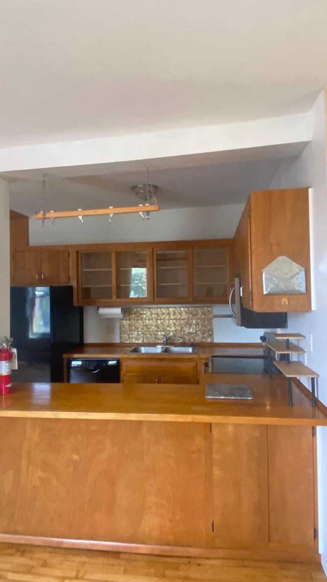 703 Laurel Ave Unit 4W, Saint Paul, MN 55104 - kitchen featuring freestanding refrigerator, a sink, brown cabinetry, black dishwasher, and tasteful backsplash