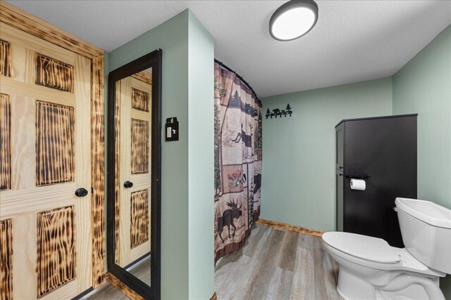 1334 105th Ave, Amery, WI 54001 - full bath featuring toilet, wood finished floors, baseboards, and a shower with shower curtain