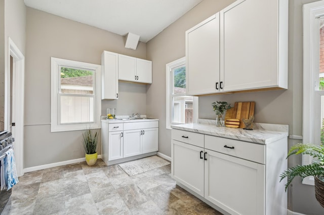 2619 23rd Ave N, Minneapolis, MN 55411 - kitchen with white cabinets, plenty of natural light, light stone countertops, and stone finish flooring