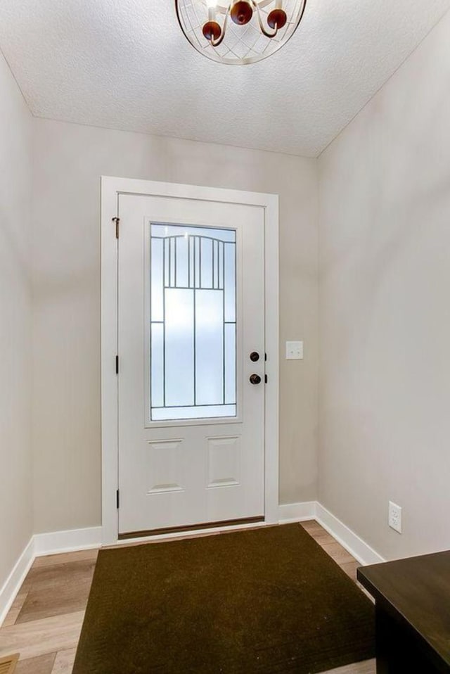 12620 Overlook Rd, Dayton, MN 55327 - entryway with light wood-style flooring, baseboards, a textured ceiling, and a chandelier