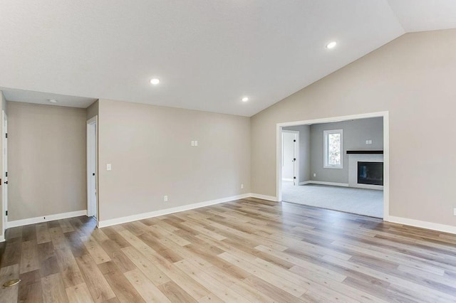 12620 Overlook Rd, Dayton, MN 55327 - unfurnished living room with vaulted ceiling, light wood finished floors, baseboards, recessed lighting, and a glass covered fireplace
