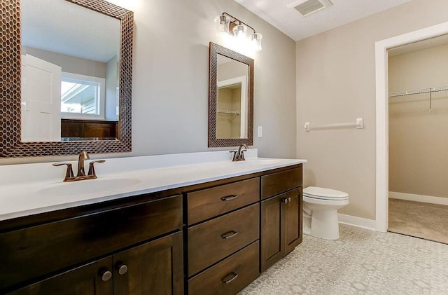 12620 Overlook Rd, Dayton, MN 55327 - bathroom with double vanity, toilet, a walk in closet, and baseboards