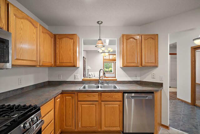 9479 Prairieview Trl N, Champlin, MN 55316 - kitchen with appliances with stainless steel finishes, a sink, dark countertops, pendant lighting, and a textured ceiling