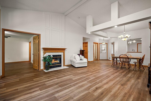 9479 Prairieview Trl N, Champlin, MN 55316 - living area with a glass covered fireplace, high vaulted ceiling, light wood-type flooring, a chandelier, and baseboards