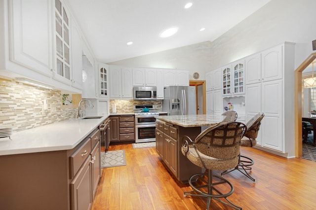22946 185th St NW, Orrock Twp, MN 55309 - kitchen featuring stainless steel appliances, light wood-style floors, a breakfast bar area, glass insert cabinets, and white cabinets