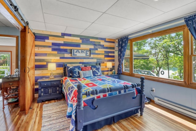 45909 Lands End Rd, Vergas, MN 56587 - bedroom with light wood finished floors, baseboard heating, a barn door, and a drop ceiling