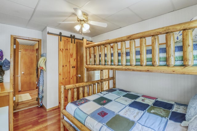 45909 Lands End Rd, Vergas, MN 56587 - bedroom with wood finished floors, a barn door, a drop ceiling, and a ceiling fan