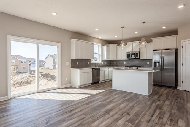 8335 Lander Ave NE, Otsego, MN 55330 - kitchen featuring stainless steel appliances, a kitchen island, white cabinetry, decorative backsplash, and dark wood-style flooring
