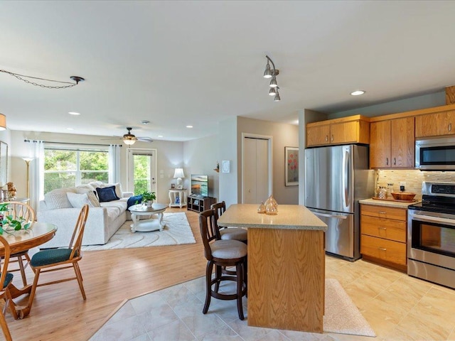8025 Dalton Rd, Baxter, MN 56425 - kitchen with appliances with stainless steel finishes, open floor plan, a kitchen island, light countertops, and tasteful backsplash