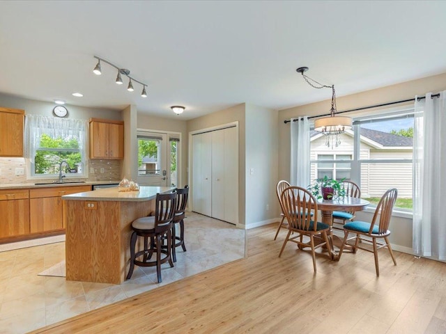 8025 Dalton Rd, Baxter, MN 56425 - kitchen with a sink, a kitchen island, tasteful backsplash, baseboards, and light wood-style flooring
