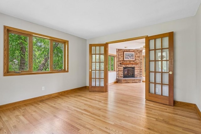 17575 Xenia St NW, Andover, MN 55304 - unfurnished living room with baseboards, light wood finished floors, french doors, and a stone fireplace