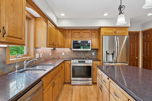 17575 Xenia St NW, Andover, MN 55304 - kitchen with stainless steel appliances, a sink, light wood-type flooring, dark stone counters, and pendant lighting