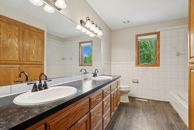 17575 Xenia St NW, Andover, MN 55304 - full bathroom with tile walls, double vanity, a bathtub, toilet, and wood finished floors