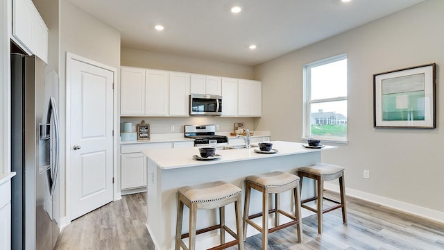6573 209th St W, Farmington, MN 55024 - kitchen featuring appliances with stainless steel finishes, light wood finished floors, a kitchen breakfast bar, light countertops, and recessed lighting