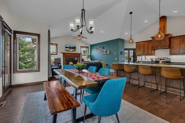 944 Cove Ct NW, Sauk Rapids, MN 56379 - dining area featuring vaulted ceiling, dark wood finished floors, a chandelier, a warm lit fireplace, and ceiling fan