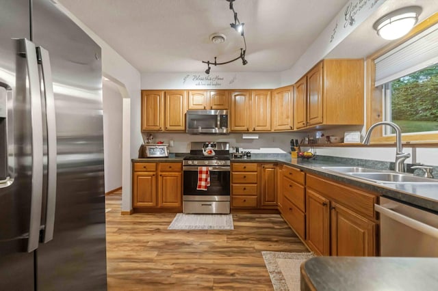 32157 County Road 39, Breezy Point, MN 56472 - kitchen with stainless steel appliances, wood finished floors, dark countertops, and brown cabinetry