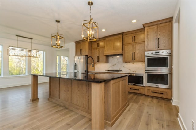 19908 67th Ave, Corcoran, MN 55340 - kitchen featuring stainless steel appliances, brown cabinetry, a chandelier, baseboards, and light wood-style floors