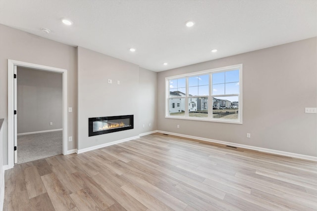 4589 Lotus Dr, Minnetrista, MN 55331 - unfurnished living room featuring a glass covered fireplace, light wood-style floors, and recessed lighting