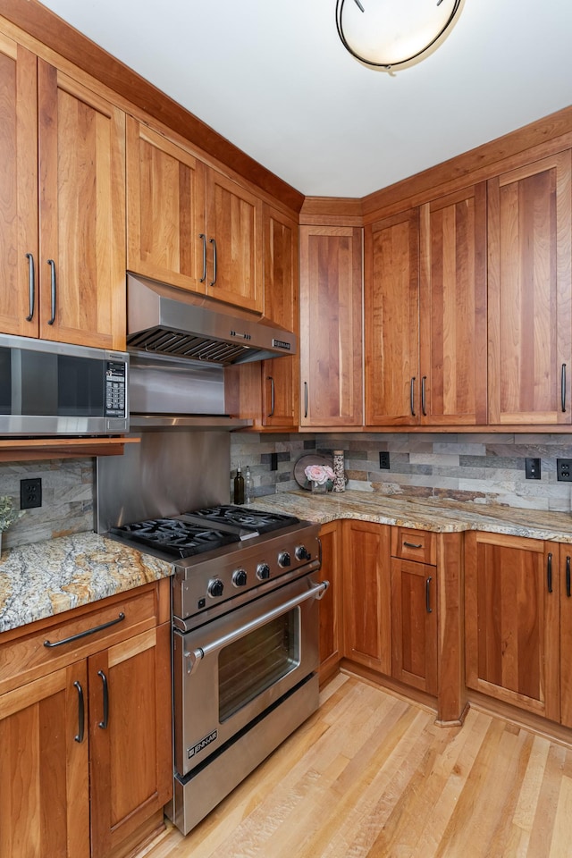 523 6th St SW, Rochester, MN 55902 - kitchen featuring stainless steel appliances, under cabinet range hood, backsplash, and brown cabinets