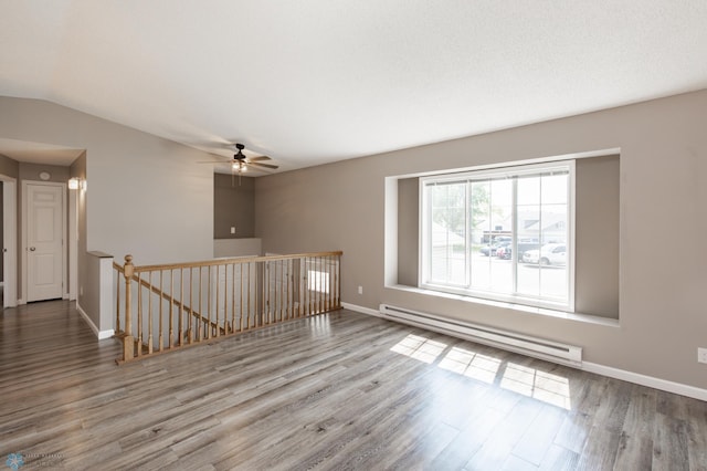 715 49th St S, Fargo, ND 58103 - empty room with a baseboard heating unit, wood finished floors, baseboards, a ceiling fan, and vaulted ceiling