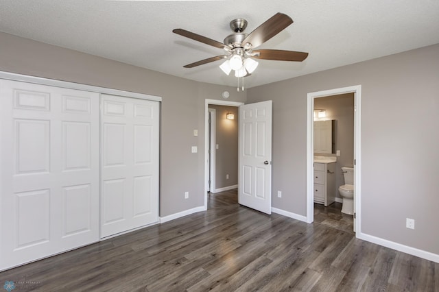715 49th St S, Fargo, ND 58103 - unfurnished bedroom featuring dark wood-style flooring, a closet, baseboards, and connected bathroom