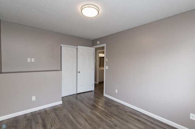 715 49th St S, Fargo, ND 58103 - unfurnished bedroom featuring baseboards, dark wood-style flooring, a closet, and a textured ceiling