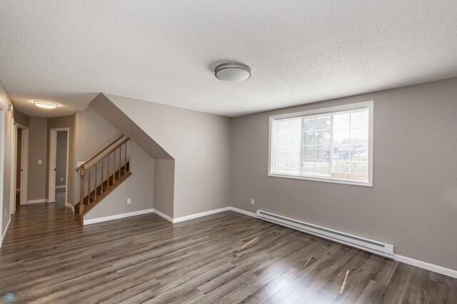 715 49th St S, Fargo, ND 58103 - unfurnished room with baseboard heating, wood finished floors, a textured ceiling, stairway, and baseboards