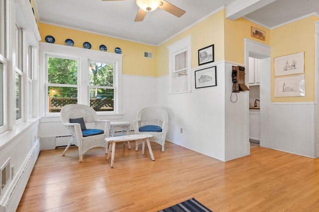 922 Fillmore St, Alexandria, MN 56308 - sitting room with a baseboard radiator, a ceiling fan, crown molding, wainscoting, and light wood-style flooring