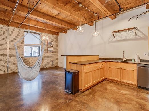 127 5th St NE Unit G08, Minneapolis, MN 55413 - kitchen with brick wall, wood ceiling with exposed beams, stainless steel dishwasher, finished concrete floors, and light brown cabinets