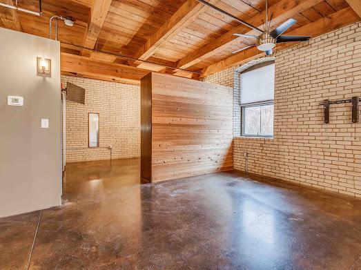 127 5th St NE Unit G08, Minneapolis, MN 55413 - unfurnished room with wood ceiling with exposed beams, brick wall, a ceiling fan, and finished concrete flooring