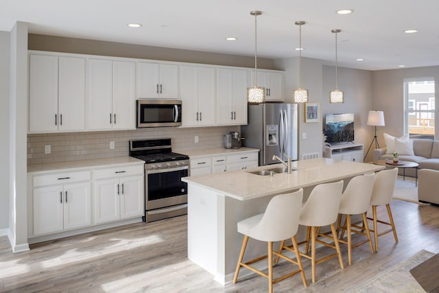 645 Satori Way, Chaska, MN 55318 - kitchen featuring stainless steel appliances, a sink, open floor plan, a center island with sink, and light wood-style flooring