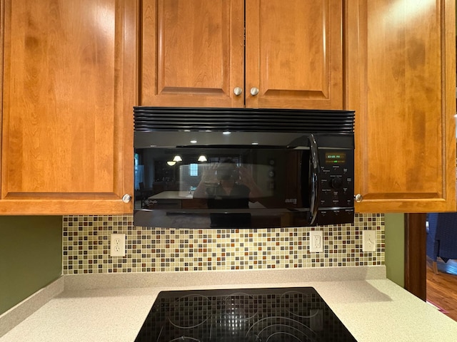 1710 Maple Ave, Benson, MN 56215 - detailed view of black appliances, light countertops, backsplash, and a glass covered fireplace