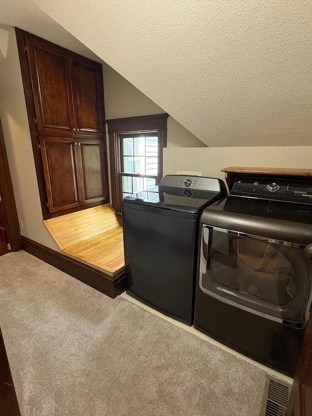1710 Maple Ave, Benson, MN 56215 - laundry room featuring washer and clothes dryer, light colored carpet, cabinet space, a textured ceiling, and baseboards