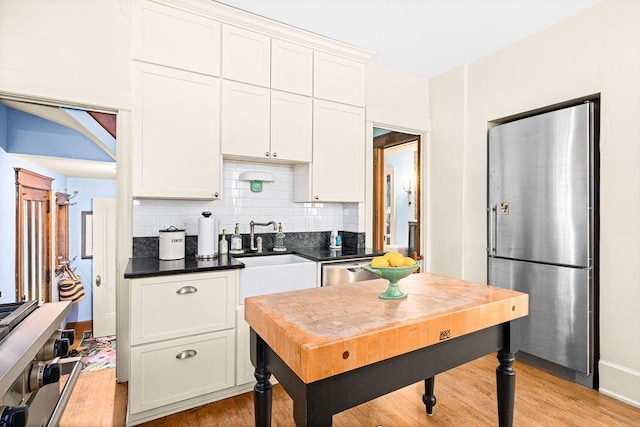 2401 5th St, Duluth, MN 55812 - kitchen featuring stainless steel appliances, light wood-style floors, decorative backsplash, dark countertops, and white cabinets