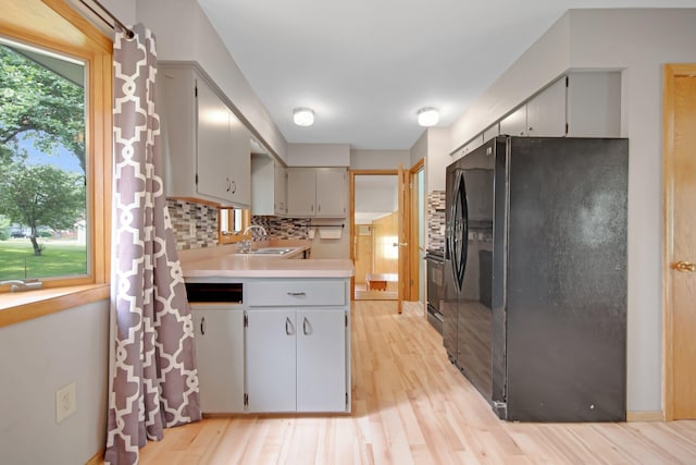1121 Ramsey St W, Stillwater, MN 55082 - kitchen with black refrigerator with ice dispenser, backsplash, light wood-type flooring, light countertops, and range