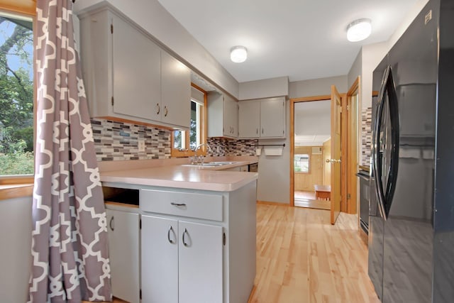 1121 Ramsey St W, Stillwater, MN 55082 - kitchen with black appliances, a peninsula, backsplash, light countertops, and light wood-style floors