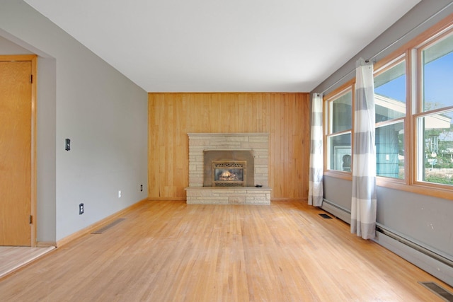 1121 Ramsey St W, Stillwater, MN 55082 - unfurnished living room with wood finished floors, wooden walls, a fireplace, and a baseboard heating unit
