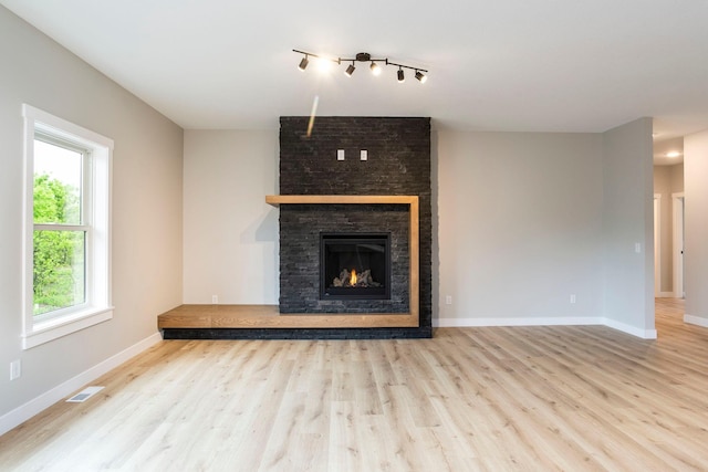 1213 54th St, Saint Joseph Twp, WI 54016 - unfurnished living room with wood finished floors, baseboards, a large fireplace, and rail lighting