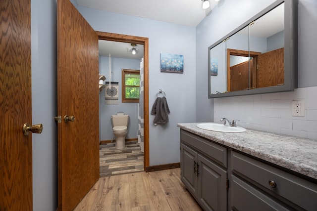 615 Eisenhower Dr, Saint Croix Falls, WI 54024 - bathroom featuring wood finished floors, backsplash, vanity, toilet, and baseboards