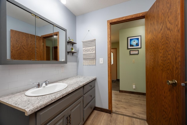 615 Eisenhower Dr, Saint Croix Falls, WI 54024 - bathroom with tasteful backsplash, wood finished floors, vanity, and baseboards