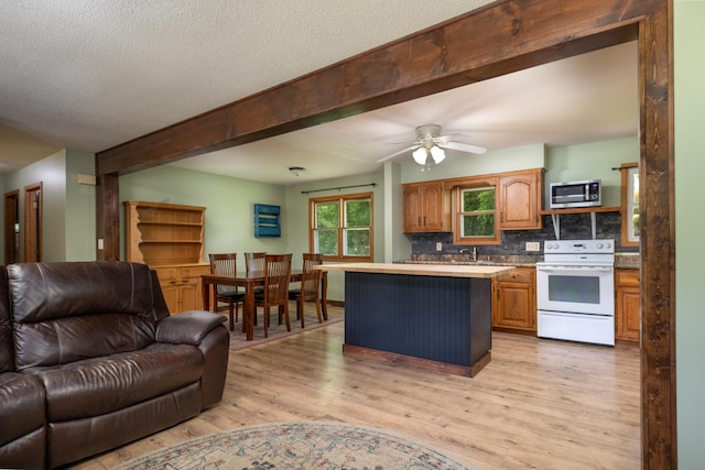615 Eisenhower Dr, Saint Croix Falls, WI 54024 - kitchen featuring white electric stove, open floor plan, stainless steel microwave, light wood-type flooring, and a kitchen island