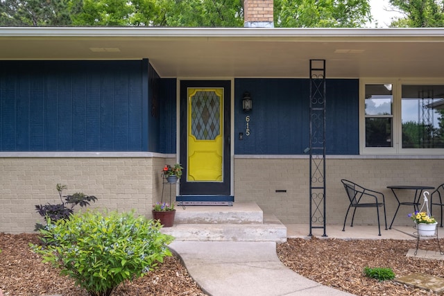 615 Eisenhower Dr, Saint Croix Falls, WI 54024 - property entrance featuring brick siding, a chimney, and a porch