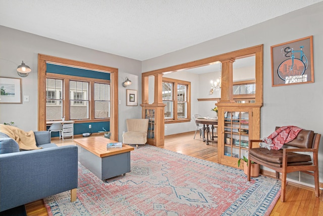 341 Pascal St S, Saint Paul, MN 55105 - living room featuring light wood-style flooring, ornate columns, and a textured ceiling
