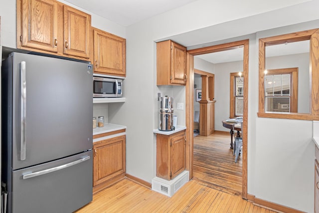 341 Pascal St S, Saint Paul, MN 55105 - kitchen featuring appliances with stainless steel finishes, light wood-style floors, light countertops, baseboards, and brown cabinets