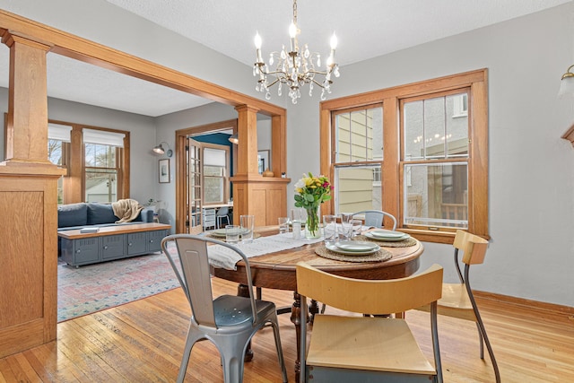 341 Pascal St S, Saint Paul, MN 55105 - dining space featuring light wood-type flooring, decorative columns, a chandelier, and baseboards